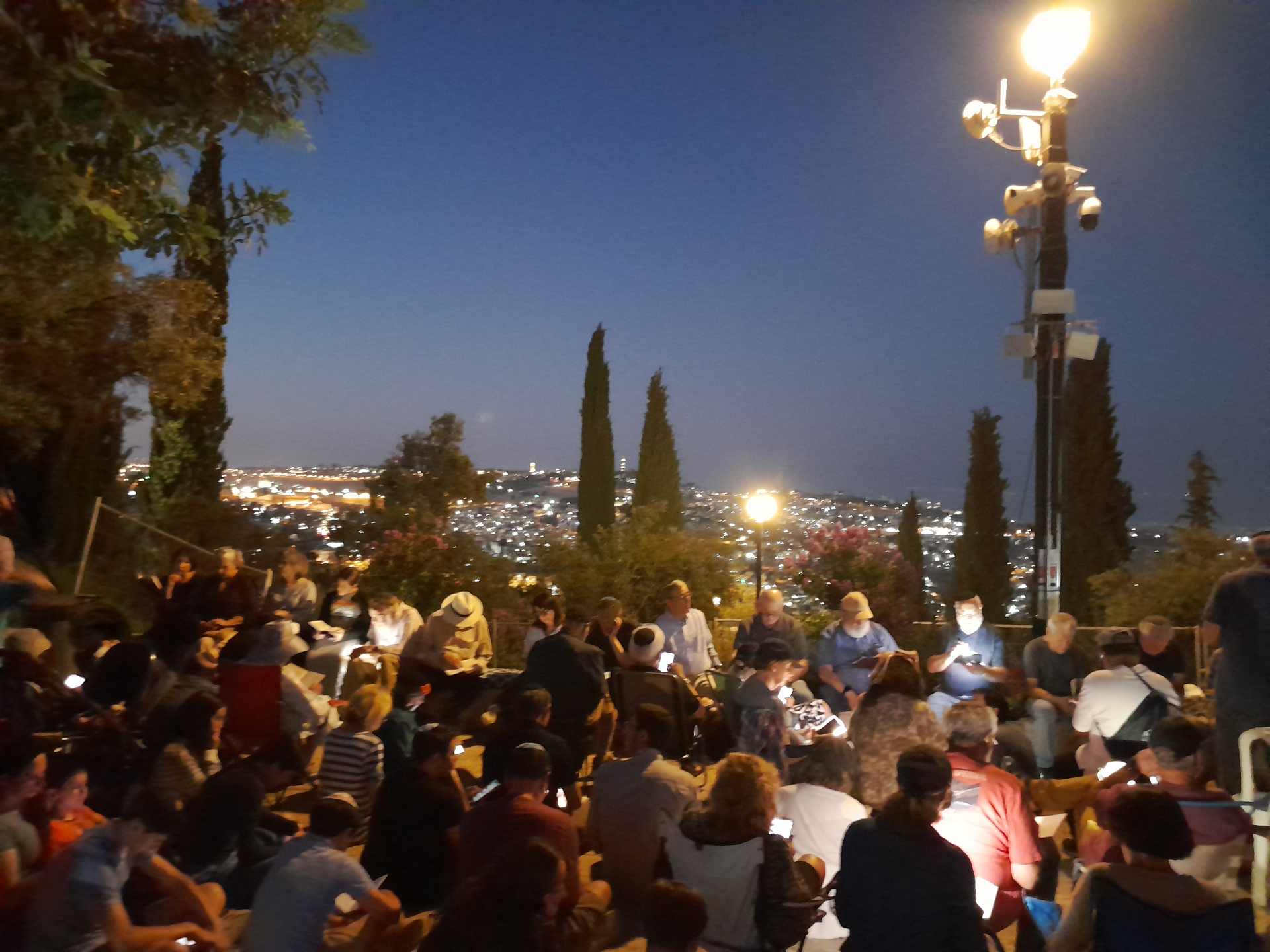 Crowd reading Megillat Eicha at the Haas Promenade in Talpiot, Jerusalem, overlooking the Old City walls at night